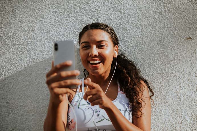 a woman smiling and taking a selfie to campanha de Dia da Mulher