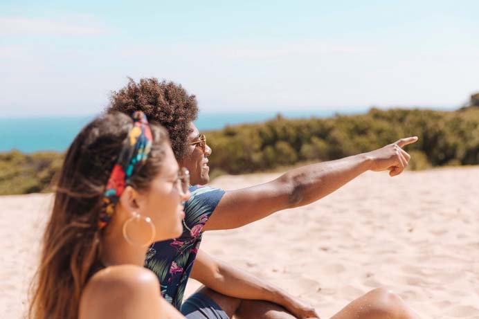 duas pessoas na praia apontando o sucesso do Liquida Verão